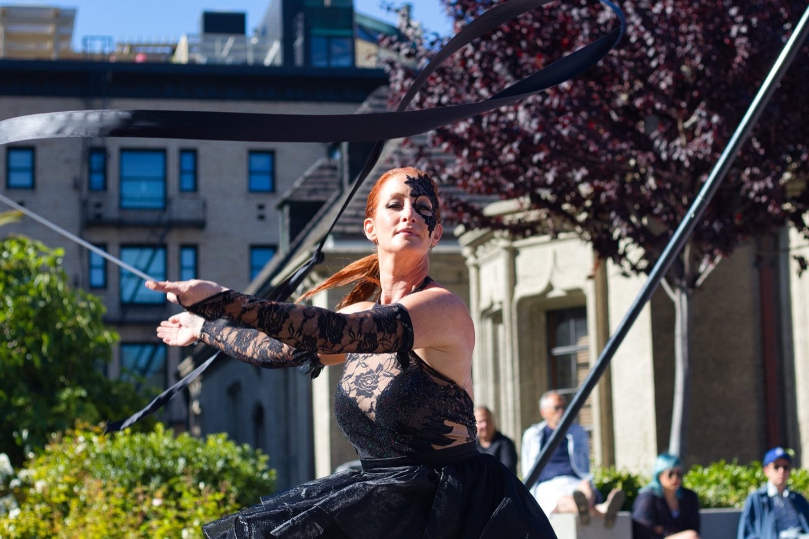 Circus performer in black lace performing outdoors for a crowd