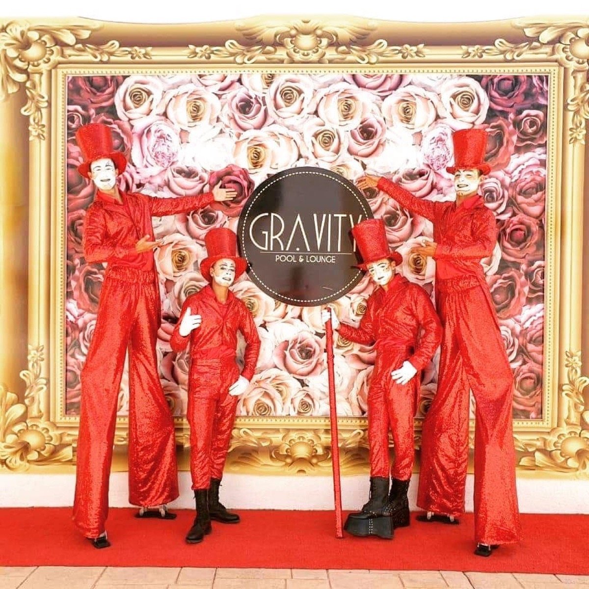Stilt walkers in red costumes and top hats greeting guests